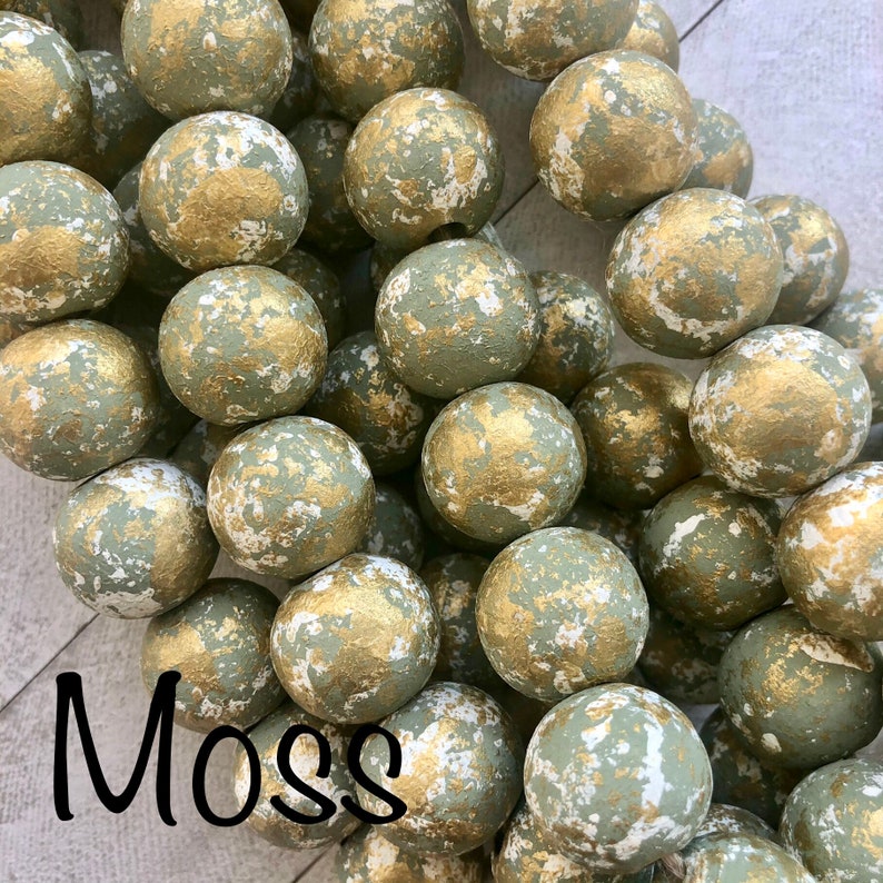Handmade gold enameled clay cross blessing bead hanging from a doorknob.