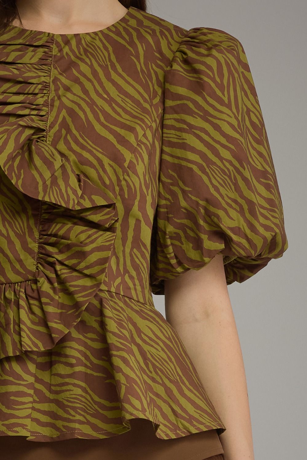 Close-up of the Serena top featuring a brown and olive zebra print with puff sleeves and ruffles.