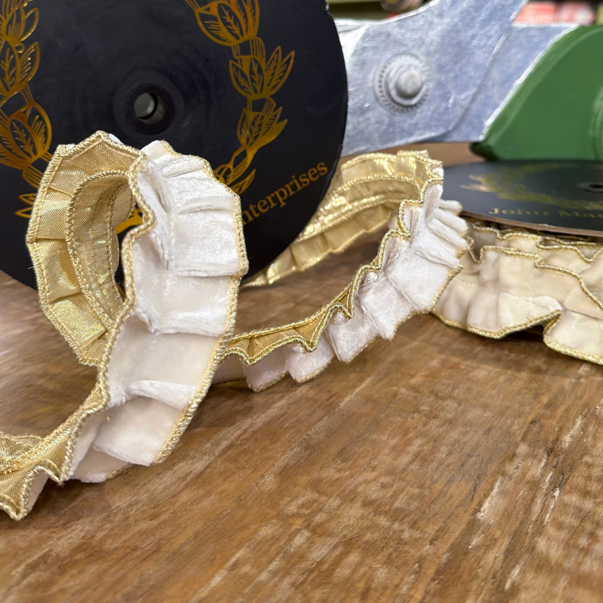 White velvet pleated ribbon with gold metallic dupion backing on a wooden surface.