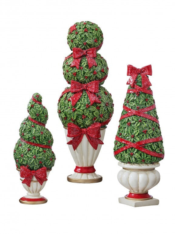Three resin holiday topiaries in white pots with green holly leaves and red glittery bows.