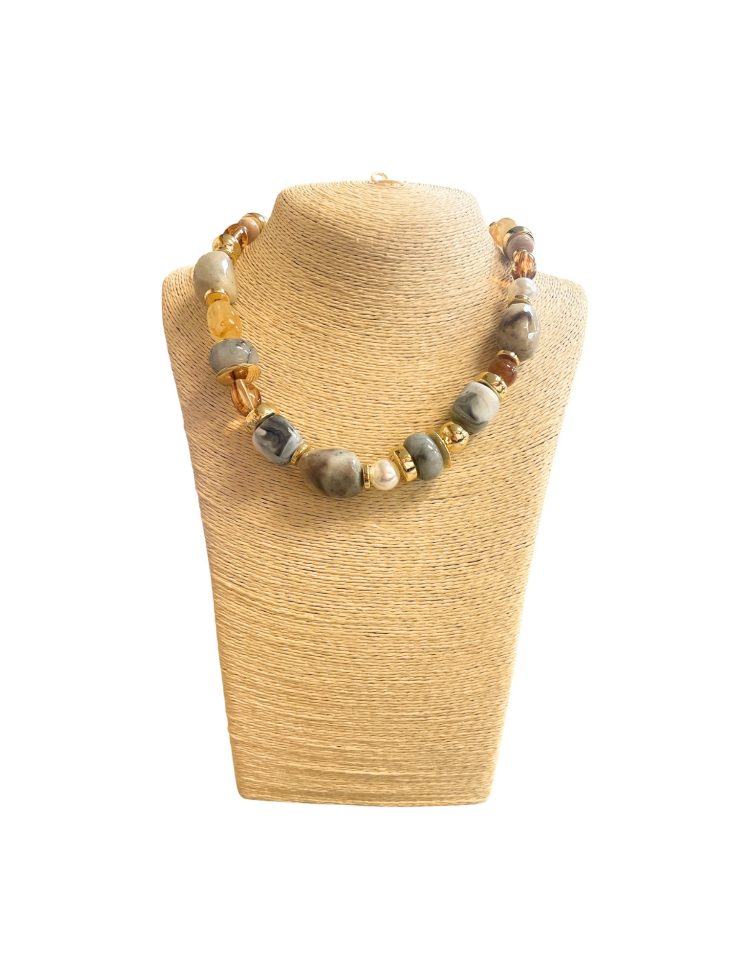 Beige multi beaded necklace with grey, amber, and gold accents on a tan jewelry bust.