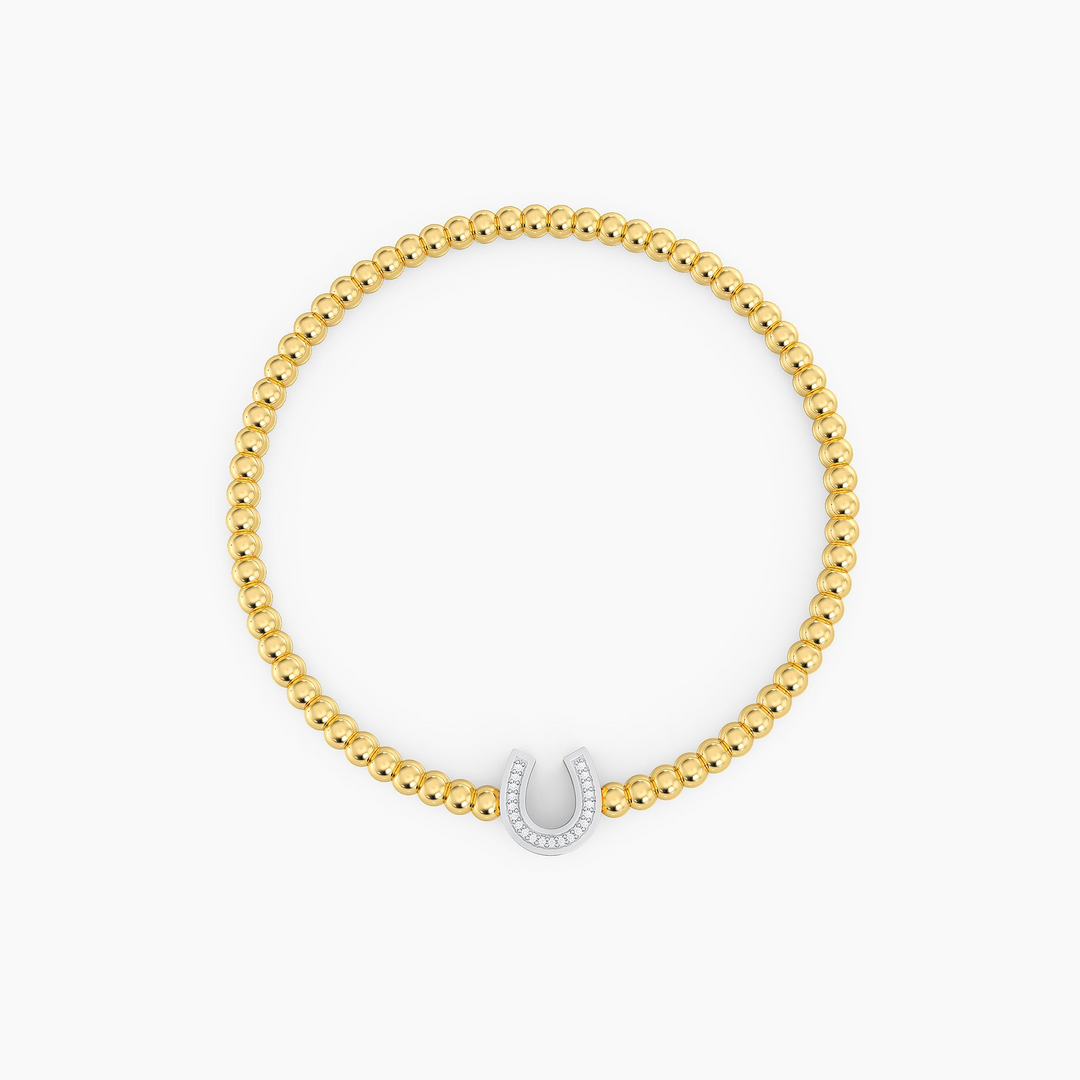 Gold beaded bracelet featuring a silver horseshoe charm set with small white diamonds.