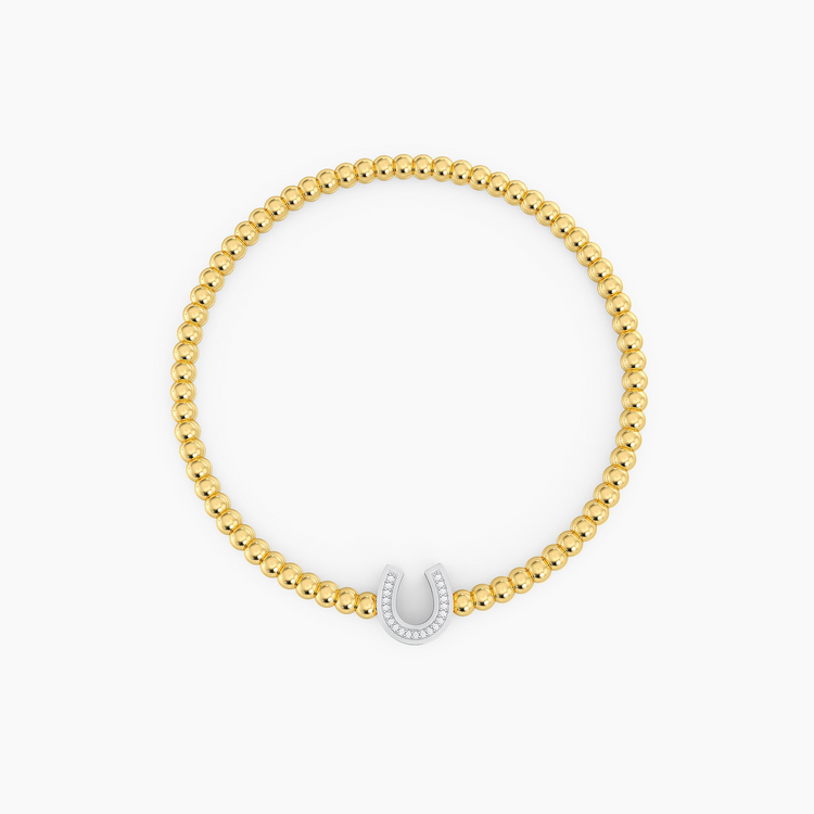 Gold beaded bracelet featuring a silver horseshoe charm set with small white diamonds.