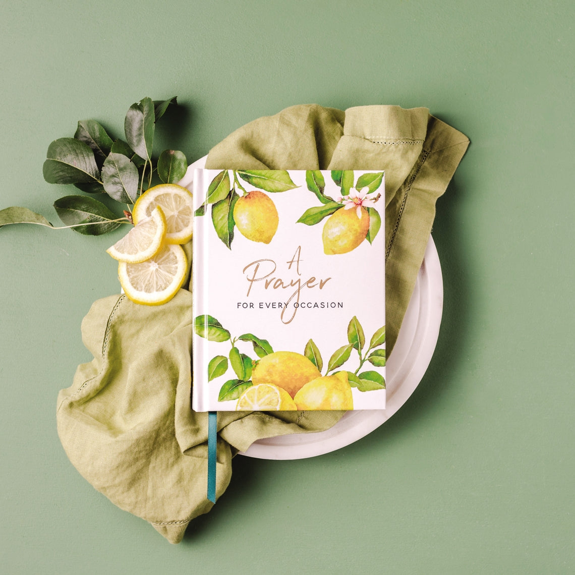 A Prayer for Every Occasion book with lemon illustrations on a green linen napkin and plate.
