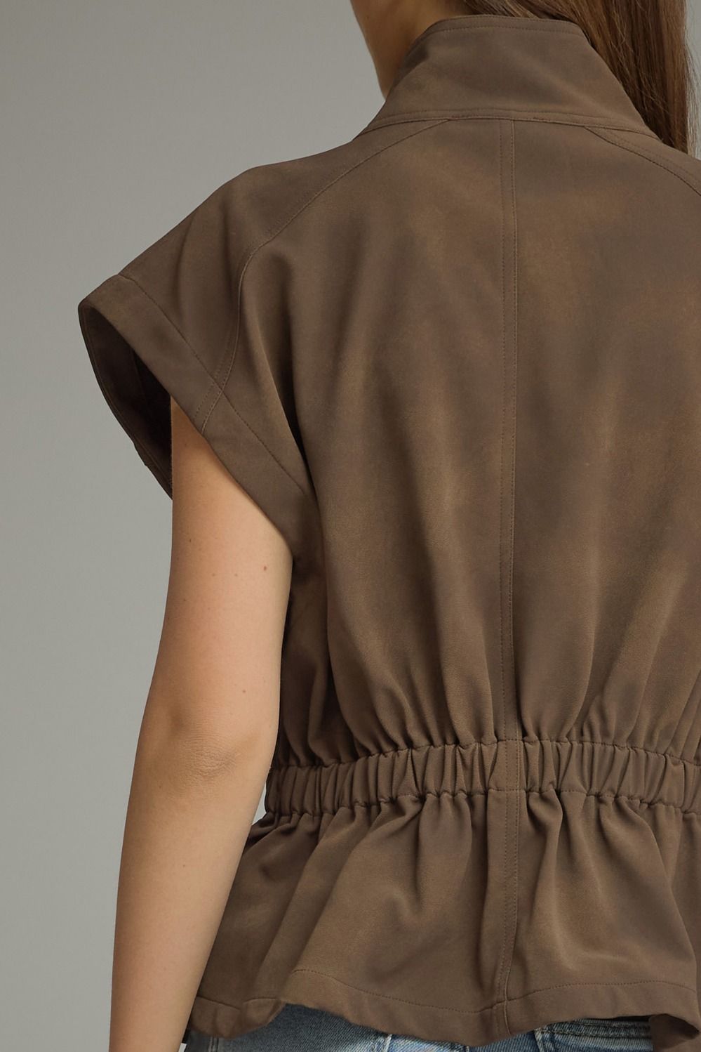 Back view of a woman wearing a brown Sarah Solid Cap Sleeve Jacket with an elastic waist.
