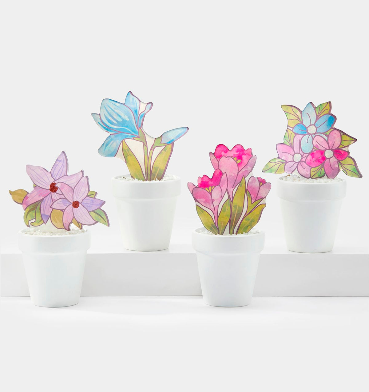 Four stained glass potted plants in white ceramic pots featuring blue, pink, and purple flowers.