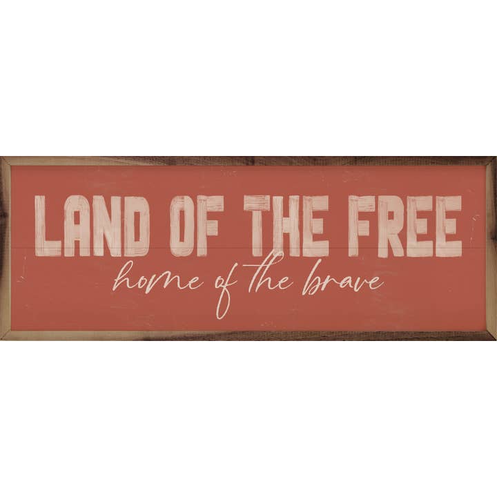Wooden sign with 'LAND OF THE FREE home of the brave' in distressed white lettering on a coral background.