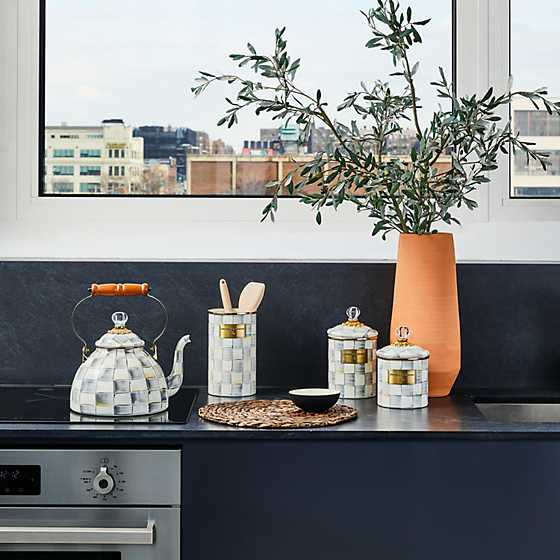 Sterling Check enamel tea kettle on a stovetop next to matching kitchen canisters and a tall vase.