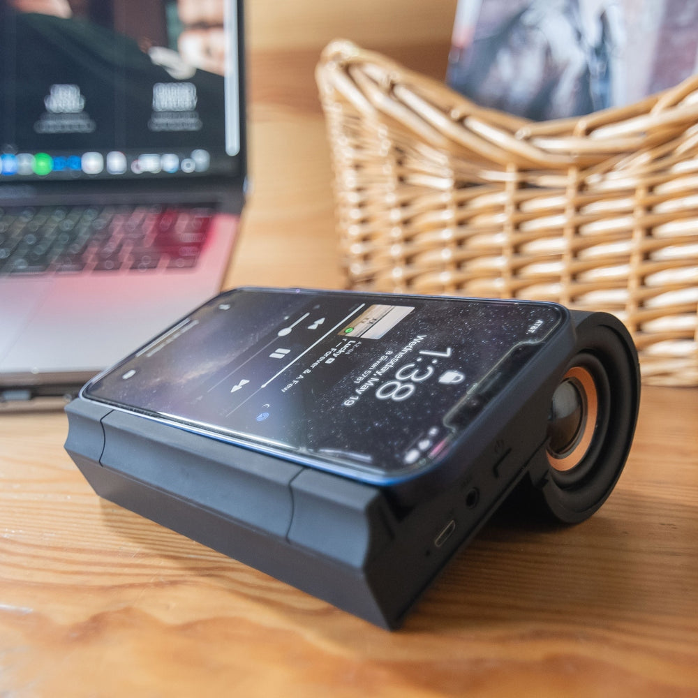 Black B1 Bluetooth desktop speaker with wireless Qi charging pad on top.