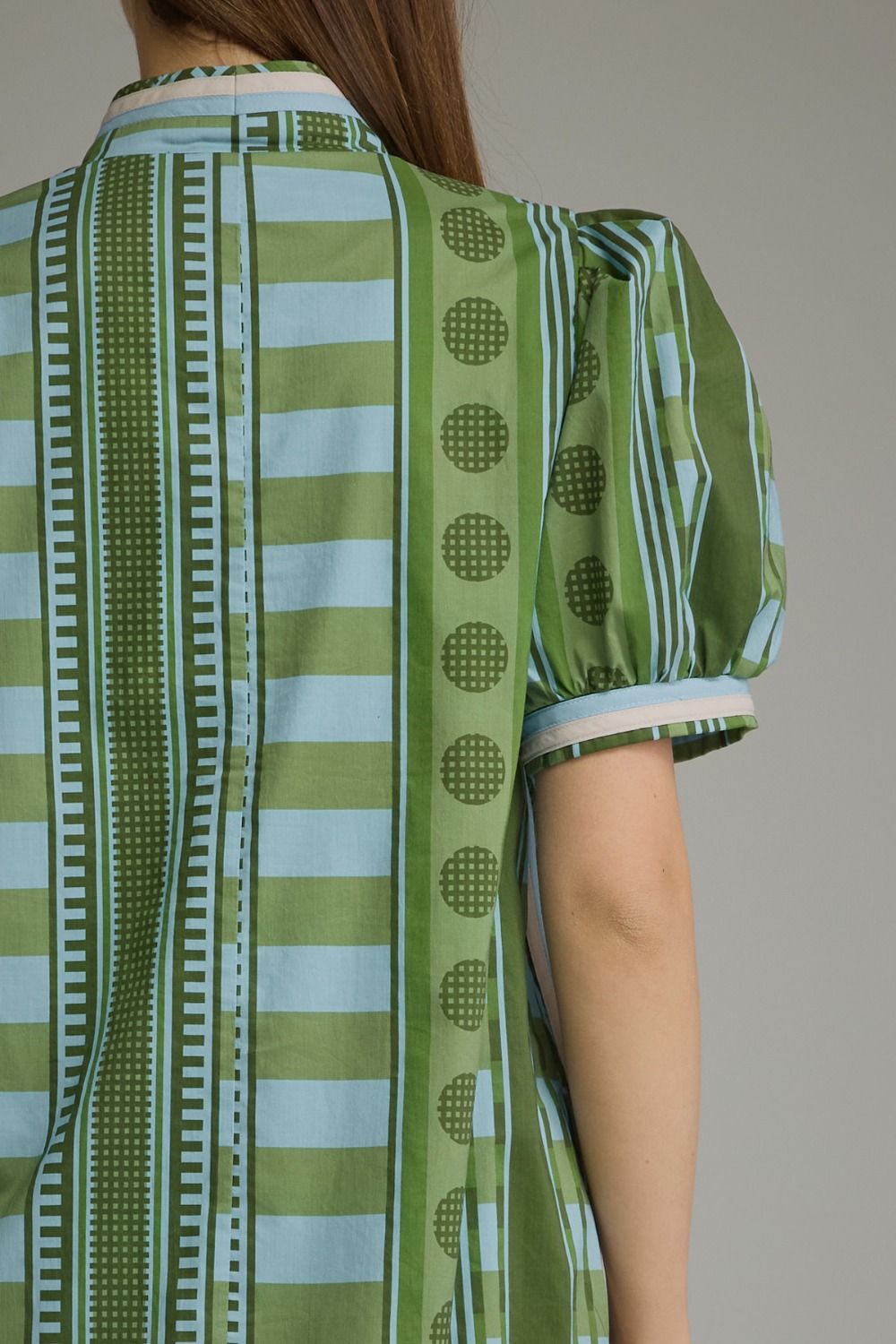 Back view of a green and blue striped mini dress with puff sleeves and geometric patterns.