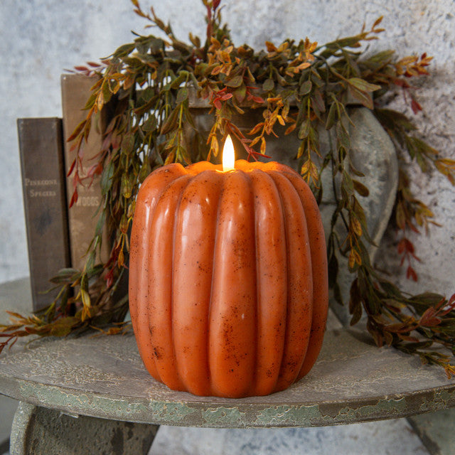 Orange 3D flame pumpkin candle with a realistic flickering LED light on a rustic wooden surface.