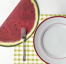 Die cut watermelon placemat sheet featuring a red fruit slice pattern with green rind and black seeds on white paper.