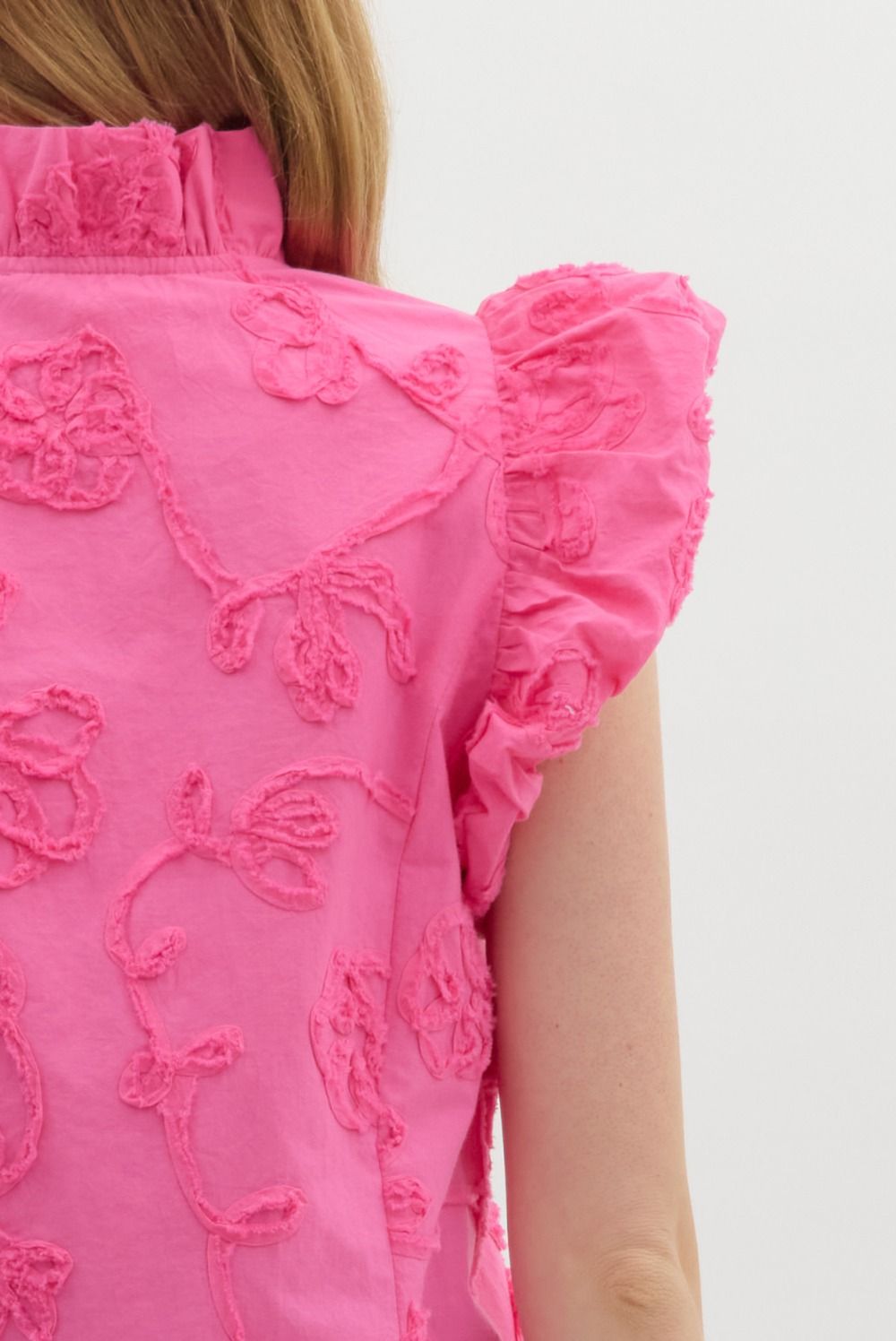 Addison top in solid cotton with floral appliqué on flutter sleeves.