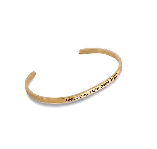 Gold-toned metal cuff bracelet engraved with the phrase CHOOSING FAITH OVER FEAR.
