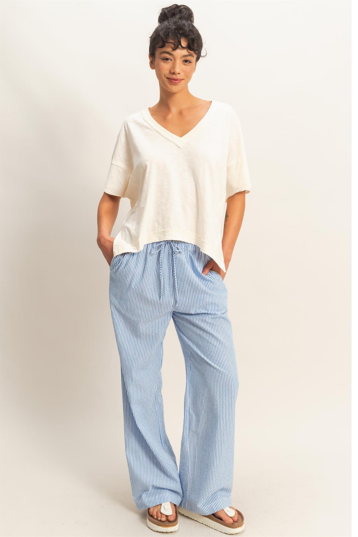 A woman wearing blue and white striped wide-leg pants with a drawstring waist and a white t-shirt.