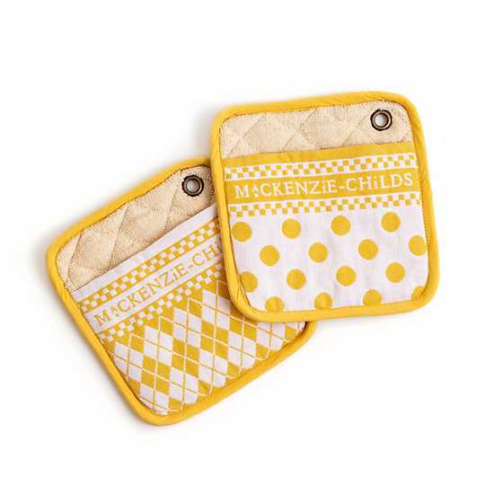 Two yellow and white Mackenzie-Childs potholders with argyle and polka dot patterns.