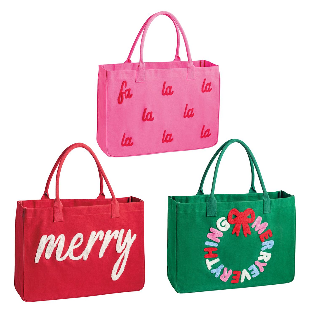 Three holiday canvas totes in pink, red, and green with festive bouclé yarn designs.
