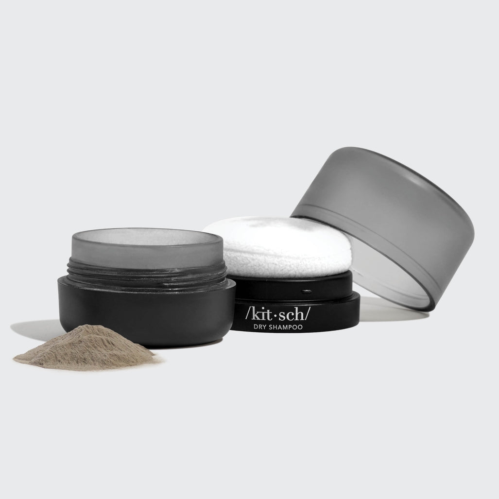Dark tinted volumizing rice protein dry shampoo powder in a travel-friendly container with built-in puff.