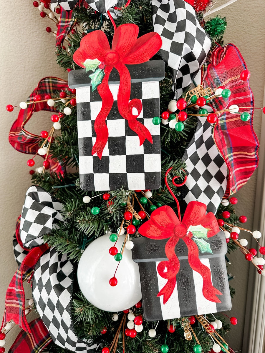 Black and white checkered gift box ornament with red ribbon and holly accent.