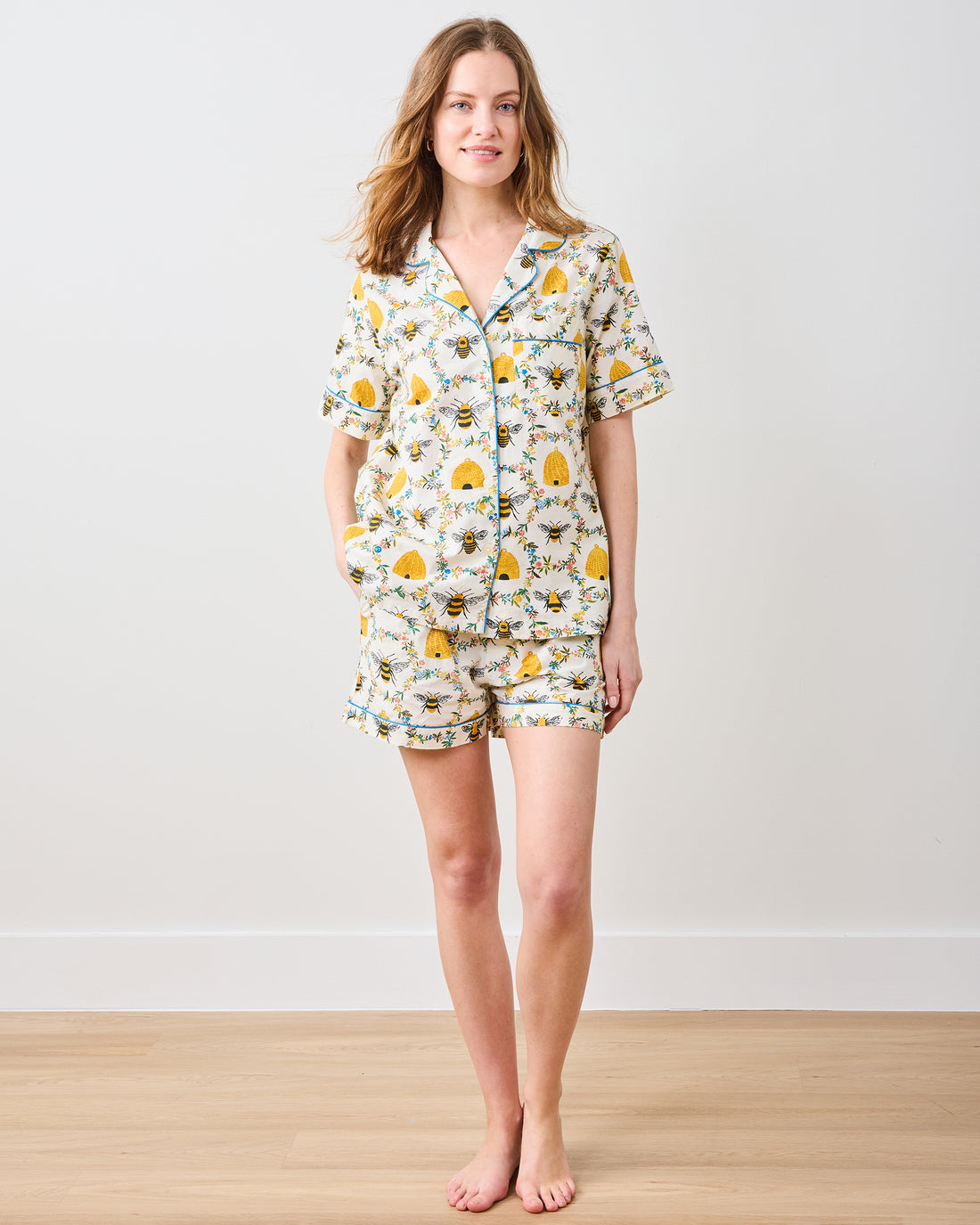 Woman wearing Arianne Short PJ Set in Sweet Bee, featuring a bee and beehive print on white cotton.