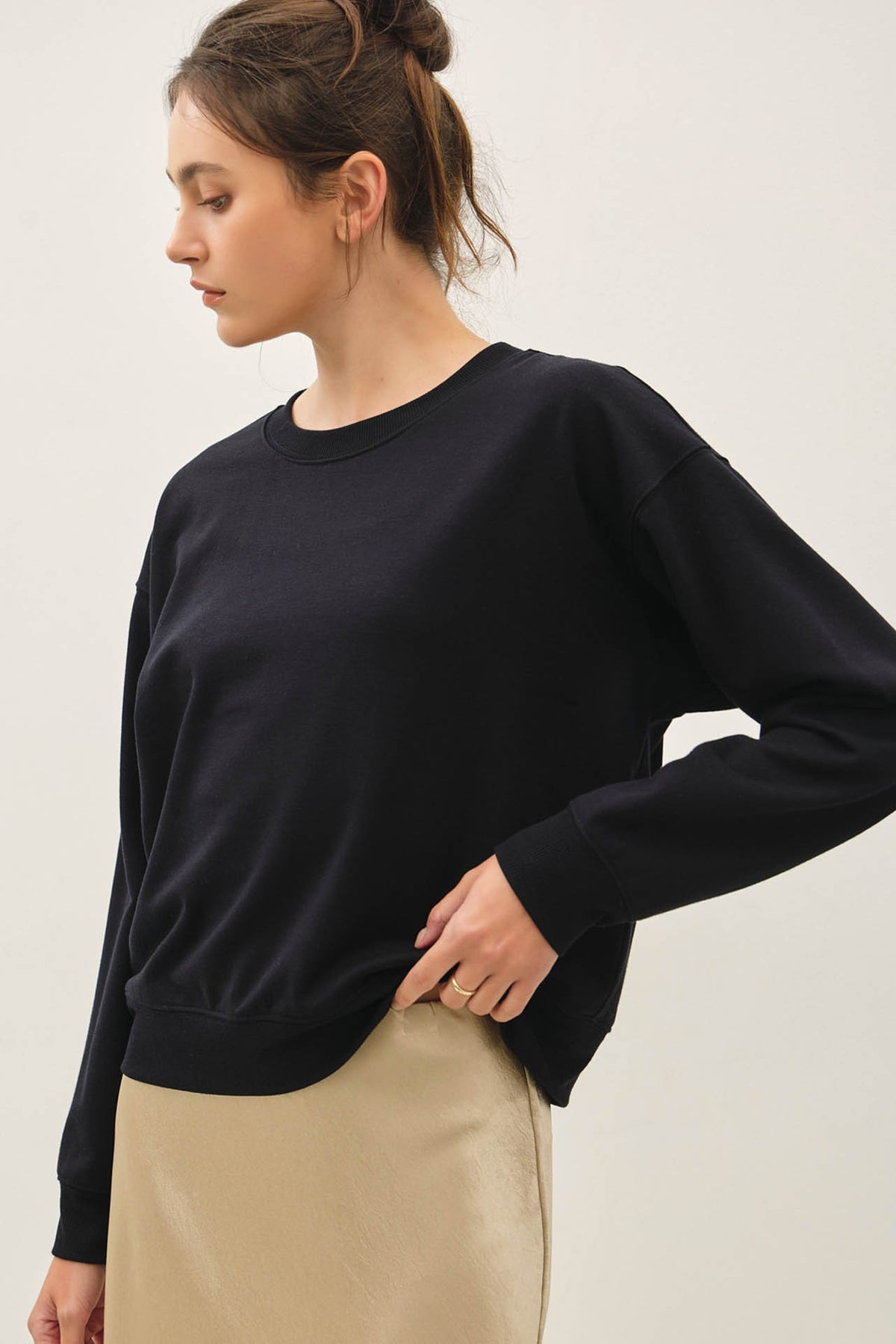 Woman wearing a black Terry Brushed Sweatshirt with a crew neckline and ribbed cuffs.