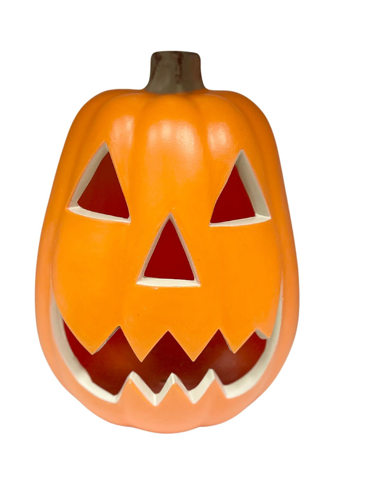 Medium lighted pumpkin with a carved jack-o'-lantern face glowing in orange.