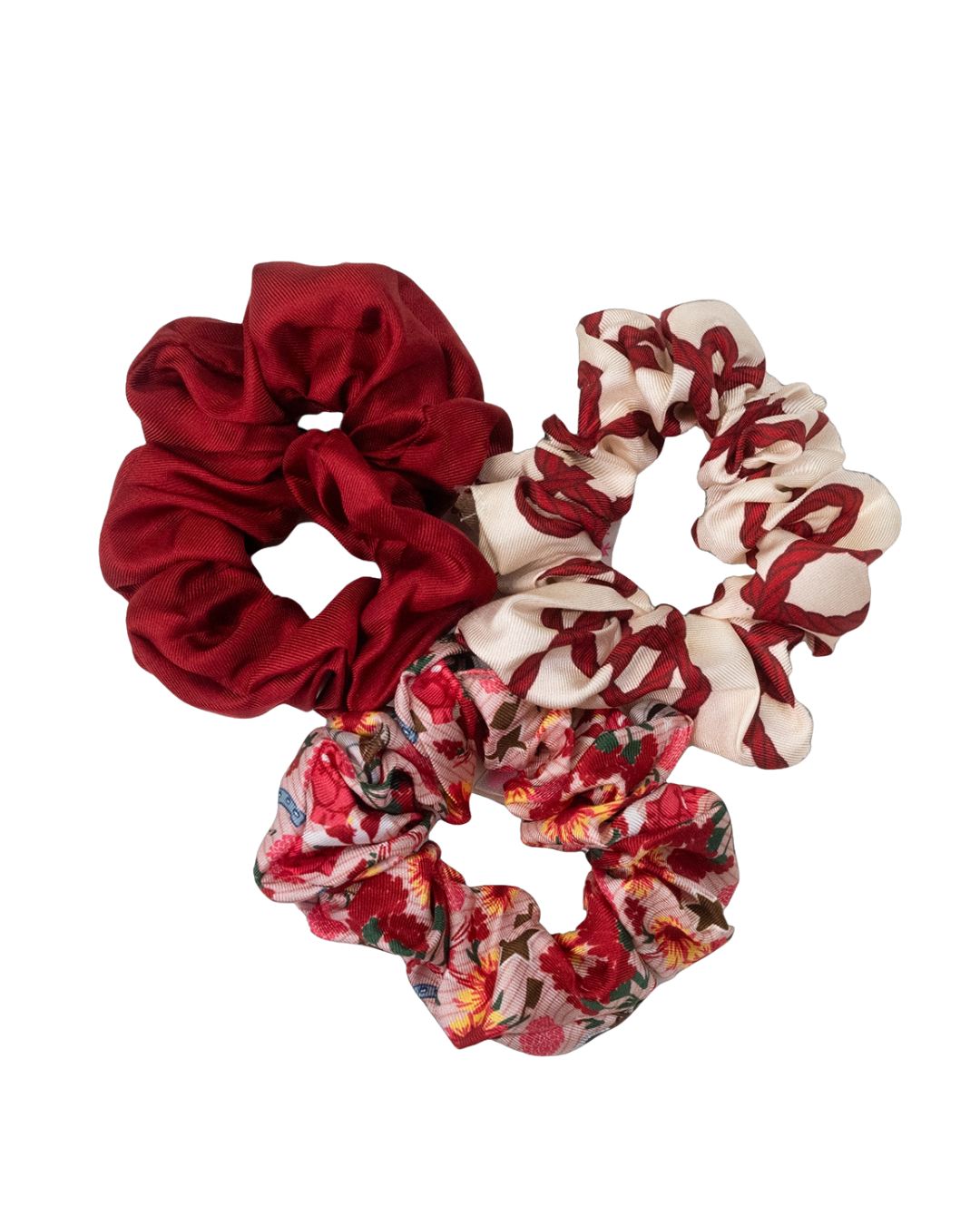 Set of three fabric scrunchies in solid red, cream with red patterns, and floral print.