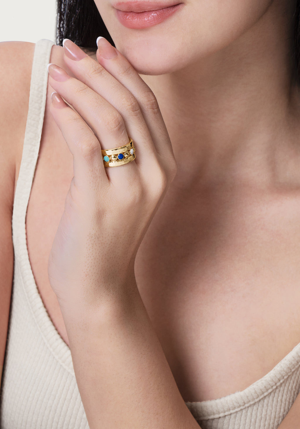 A woman wearing the Milos Multicolor Ring, a wide 18K gold plated band with colorful enamel dots.