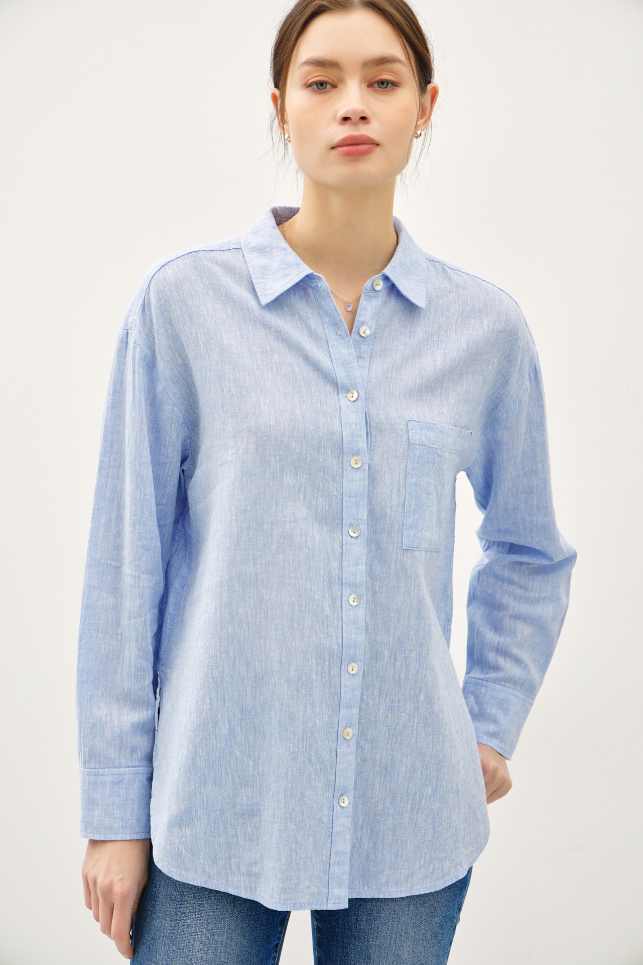 Woman wearing a light blue Madison linen blend long sleeve button-up shirt with a chest pocket.