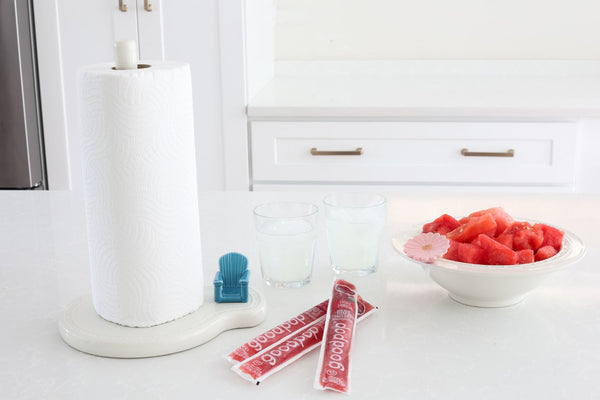 A small blue Adirondack chair figurine sits on a white paper towel holder base next to snacks.