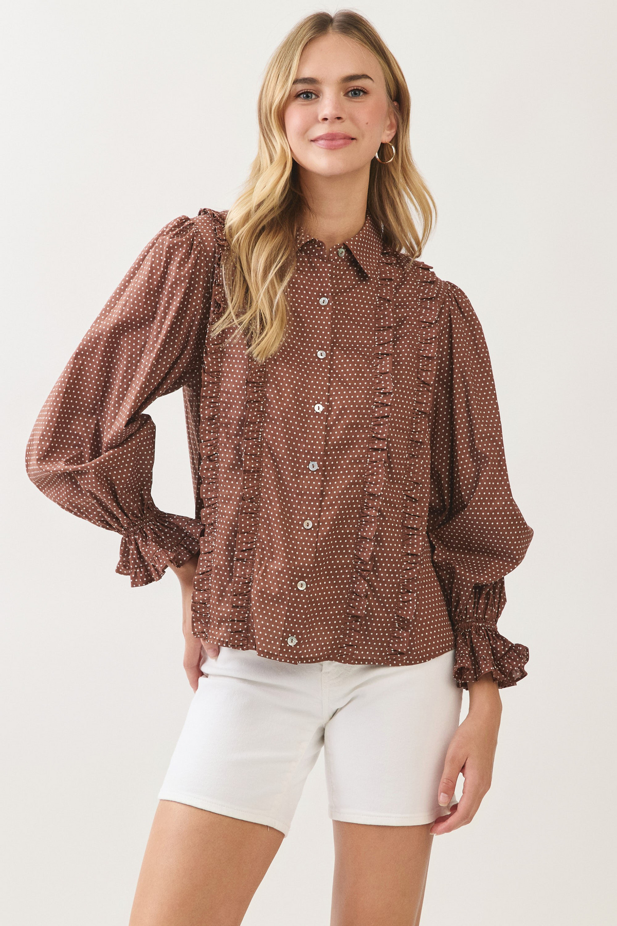 Woman wearing the brown Willa Polka Dot Button Down Shirt with white shorts.