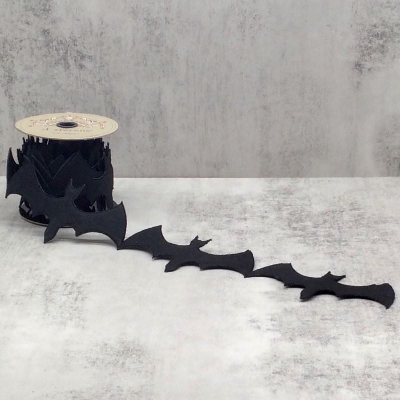 A spool of 4-inch black bat garland unrolled on a grey surface for Halloween decoration.