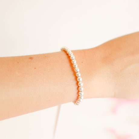 Silver beaded bracelet featuring small round beads with a sleek cylindrical shape.