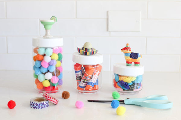 Three Pinstripes Canisters in various sizes filled with craft supplies on a white counter.