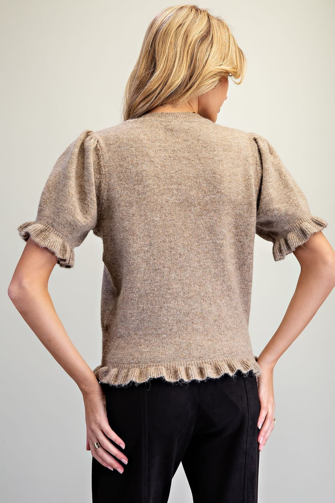 Back view of a tan short-sleeve knit cardigan with puff shoulders and ruffle trim on cuffs and hem.