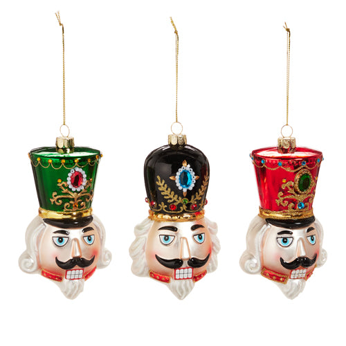 Three glass nutcracker head ornaments with green, black, and red hats and gold hanging strings.