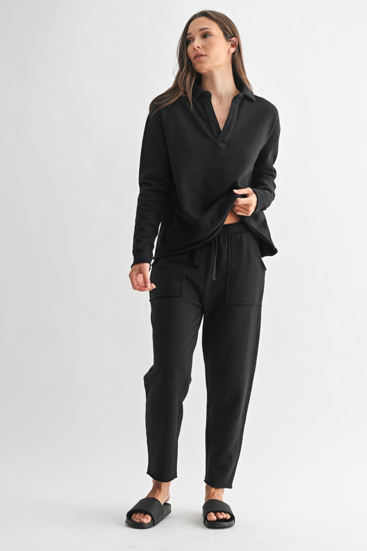 Woman wearing a black long-sleeve Virginia Malibu Vintage Henley Tee with matching sweatpants.