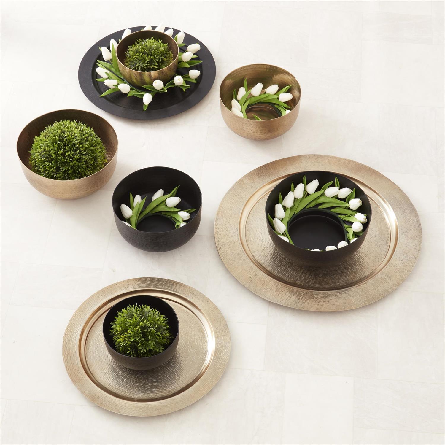 Collection of textured antiqued gold and black aluminum bowls and trays with decorative greenery.