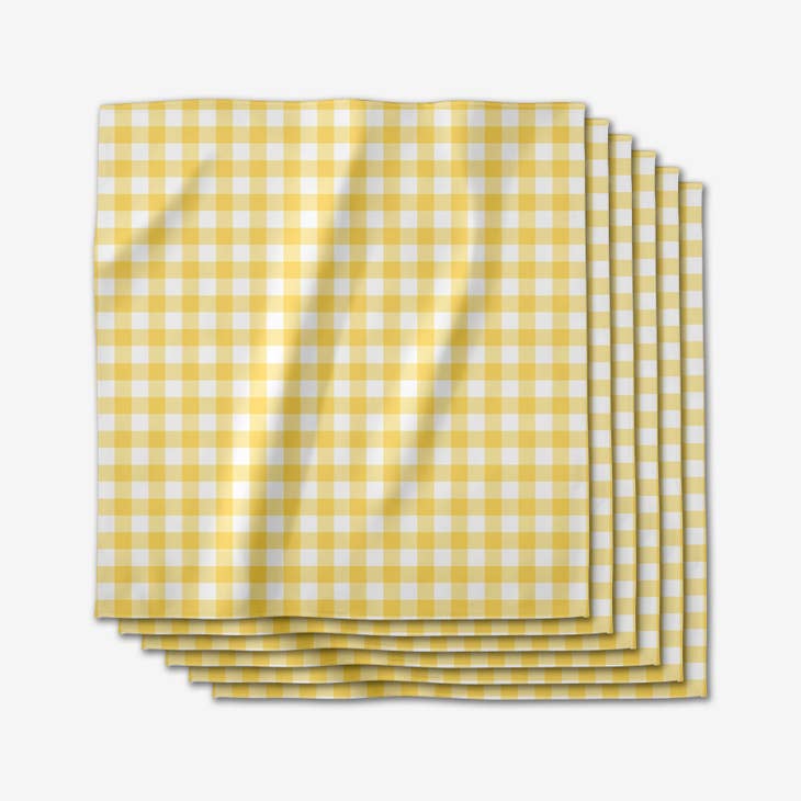 Set of six yellow and white gingham check dinner napkins stacked together.