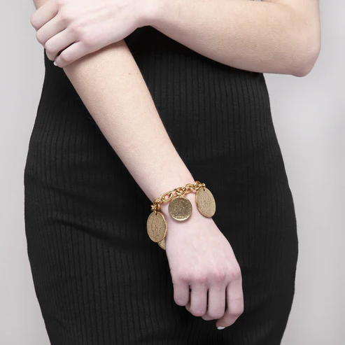 A person wearing the Piera Gold Bracelet, a 22K gold-plated chain with hanging coin charms.