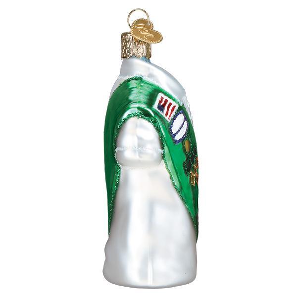 Side view of a glass Girl Scout uniform ornament featuring a green sash with colorful merit badges.