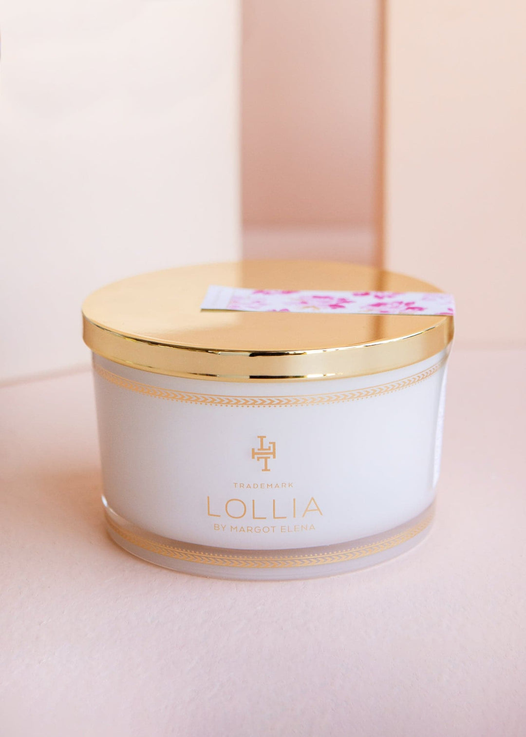 White glass jar with gold accents holding sea salt in a linen bag