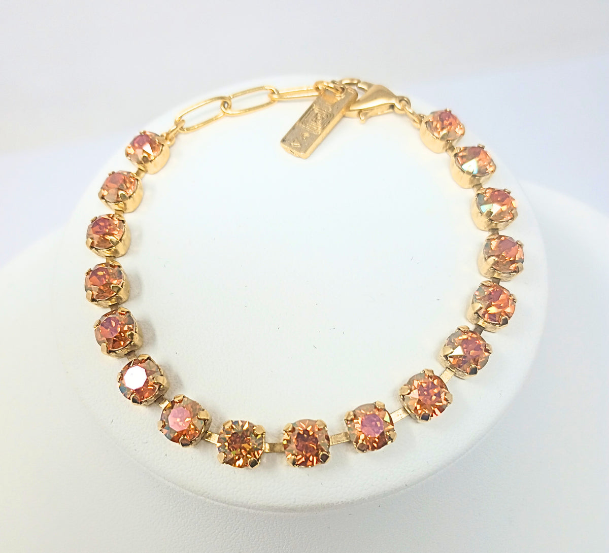Sarina Bracelet featuring amber-colored crystals in antique gold plating on a white display stand.
