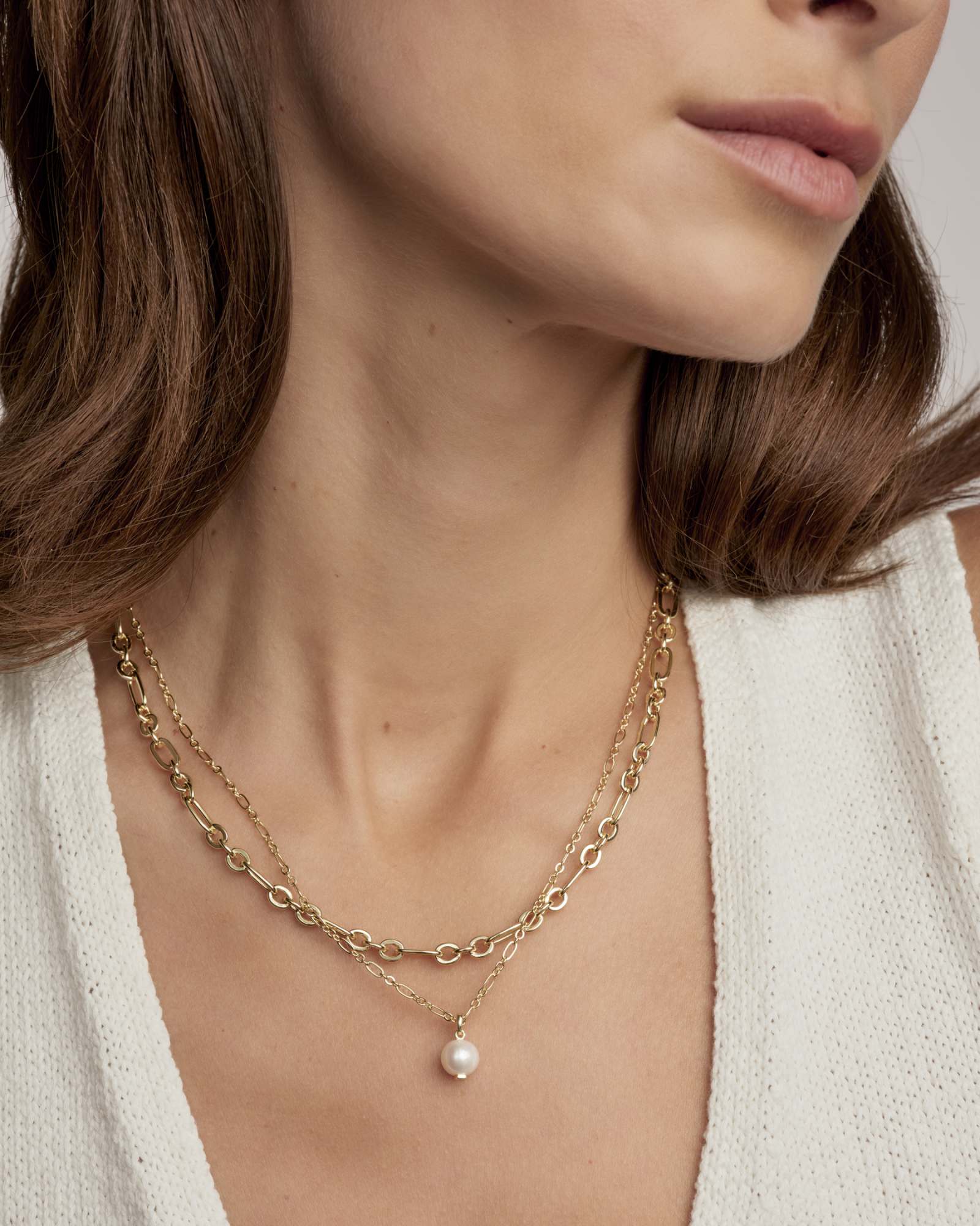 Close-up of a person wearing the Ashton Multi Strand gold chain necklace with a pearl pendant.