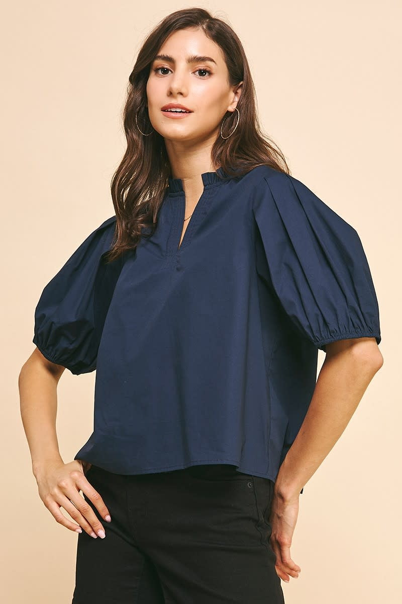 Deep navy woven V-neck top with puff sleeves and ruffle neckline detail.