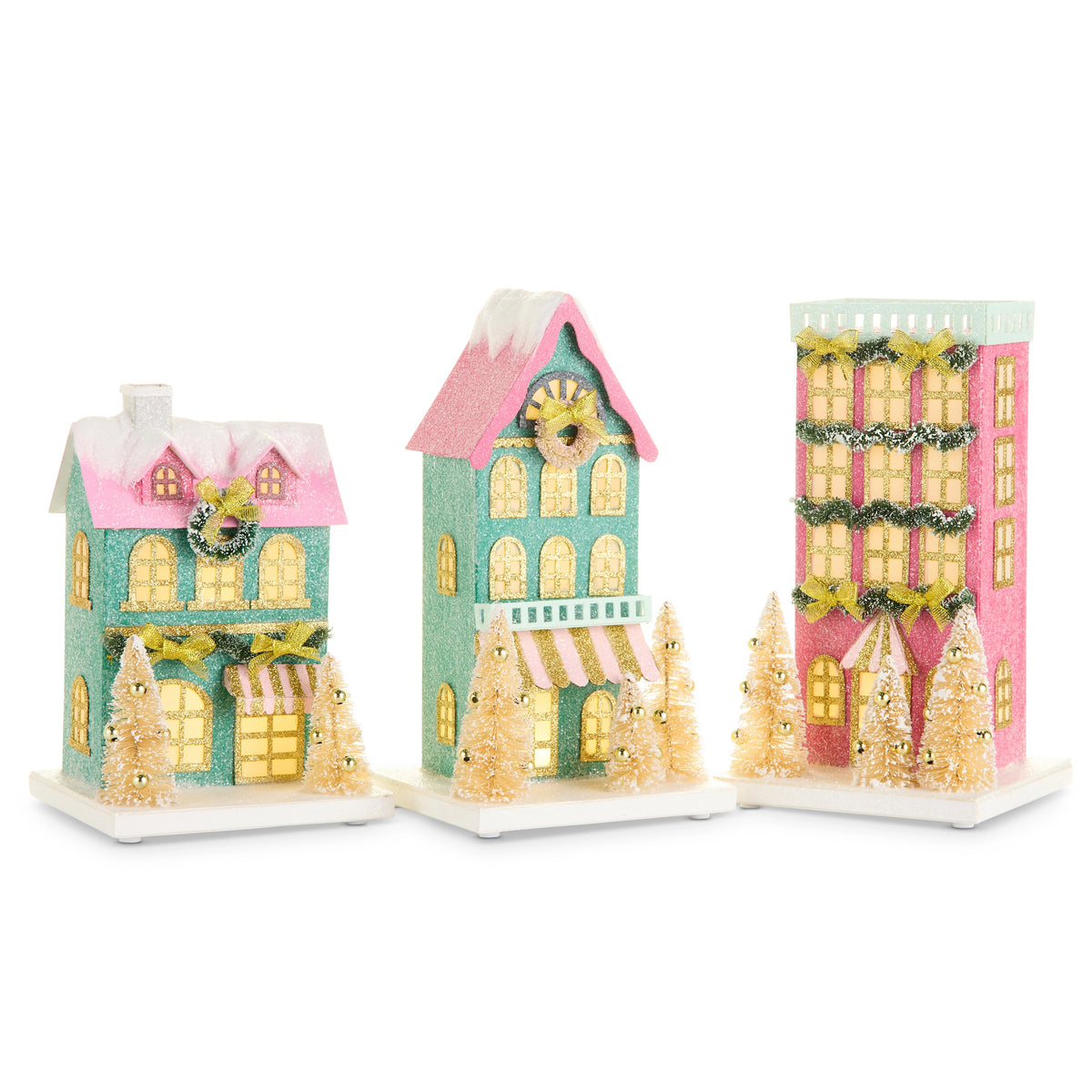 Three whimsical, lighted paper Christmas village houses in pink and teal with glitter and sisal trees.