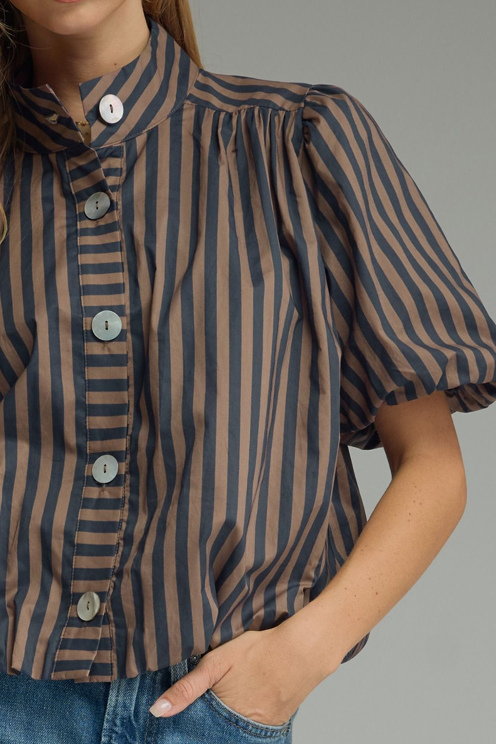 Close-up of a brown and navy striped short puff sleeve top with a band collar and button front.