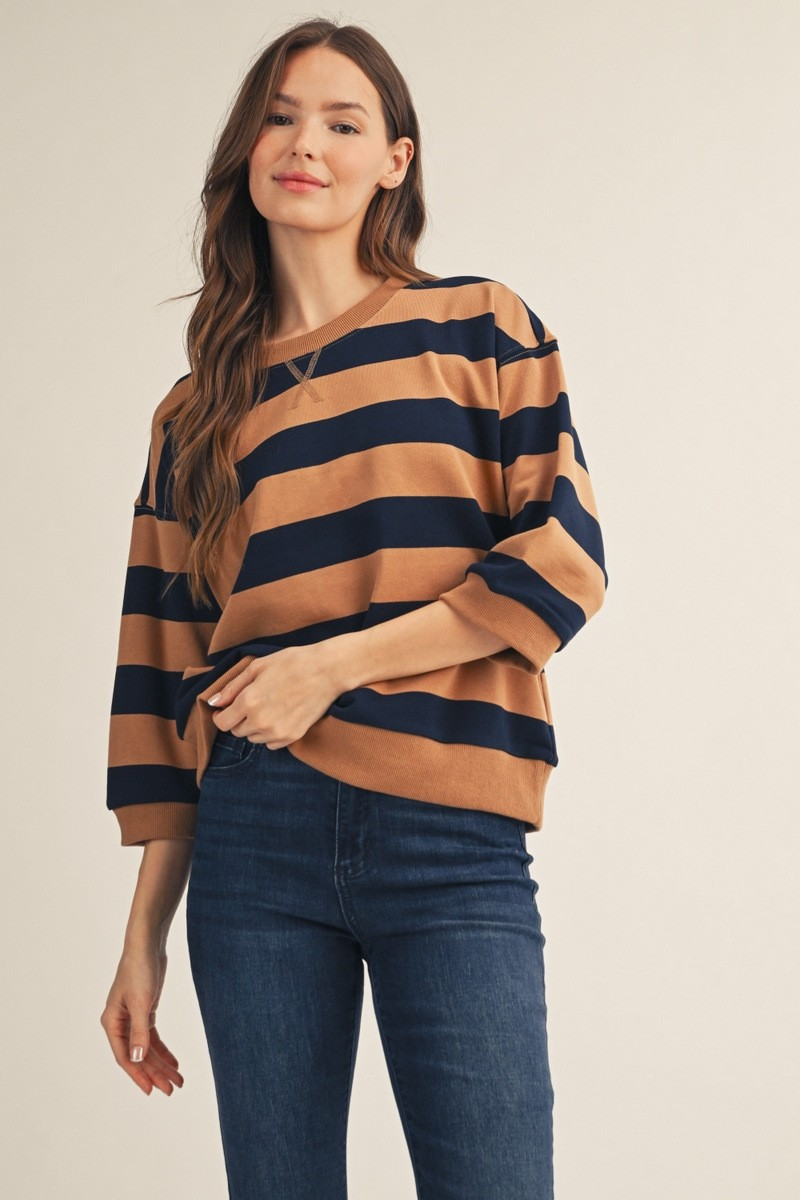 Woman wearing a brown and navy bold striped casual top with a V-notch neckline and 3/4 sleeves.