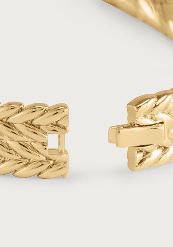 Close-up of the clasp and braided texture of a thick 18K gold plated hinged bangle.