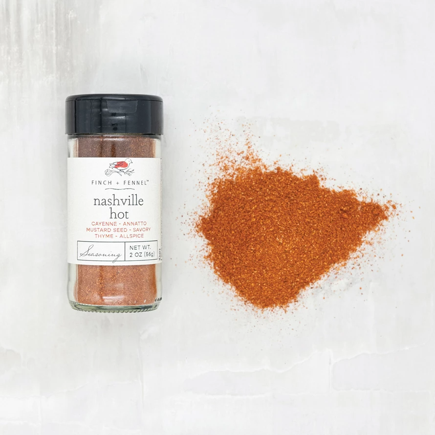 Nashville Hot Seasoning in a glass jar next to a pile of the red spice blend.
